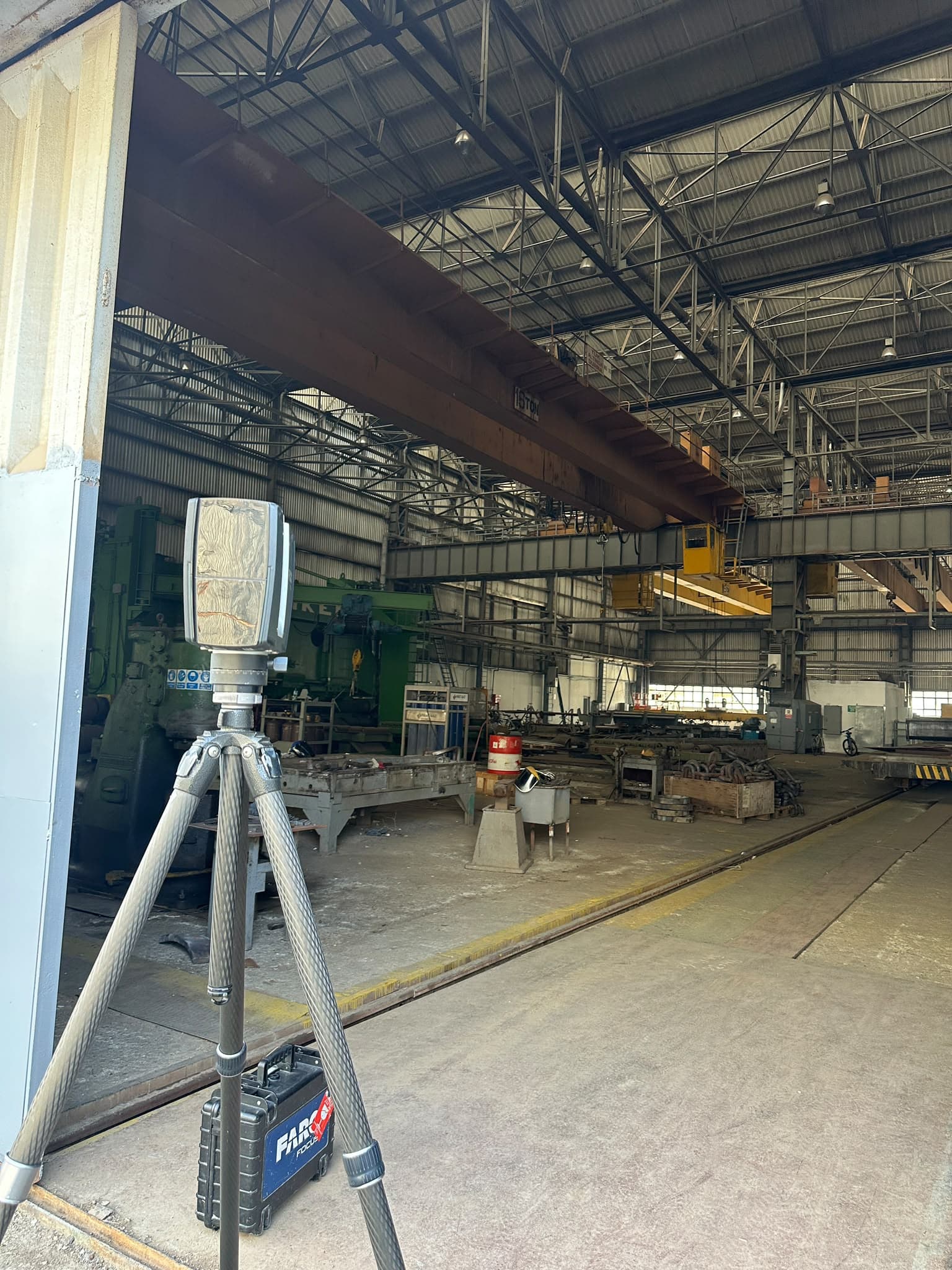 FARO scanner positioned near a bay door inside the plant, with an overhead 15-ton crane and steel stock visible